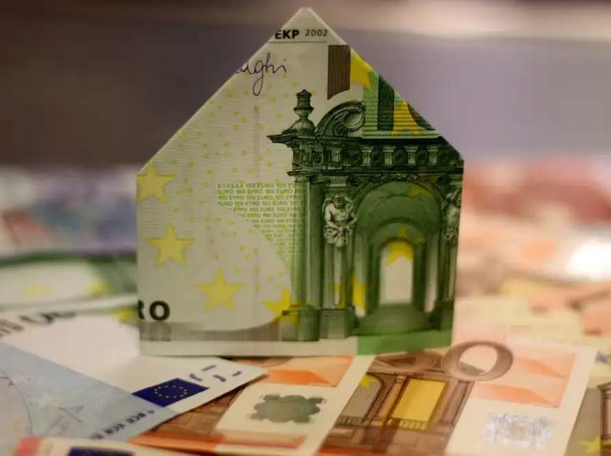 Χαρτονόμισμα ευρώ διπλωμένο σε σχήμα σπιτιού πάνω σε χαρτονομίσματα