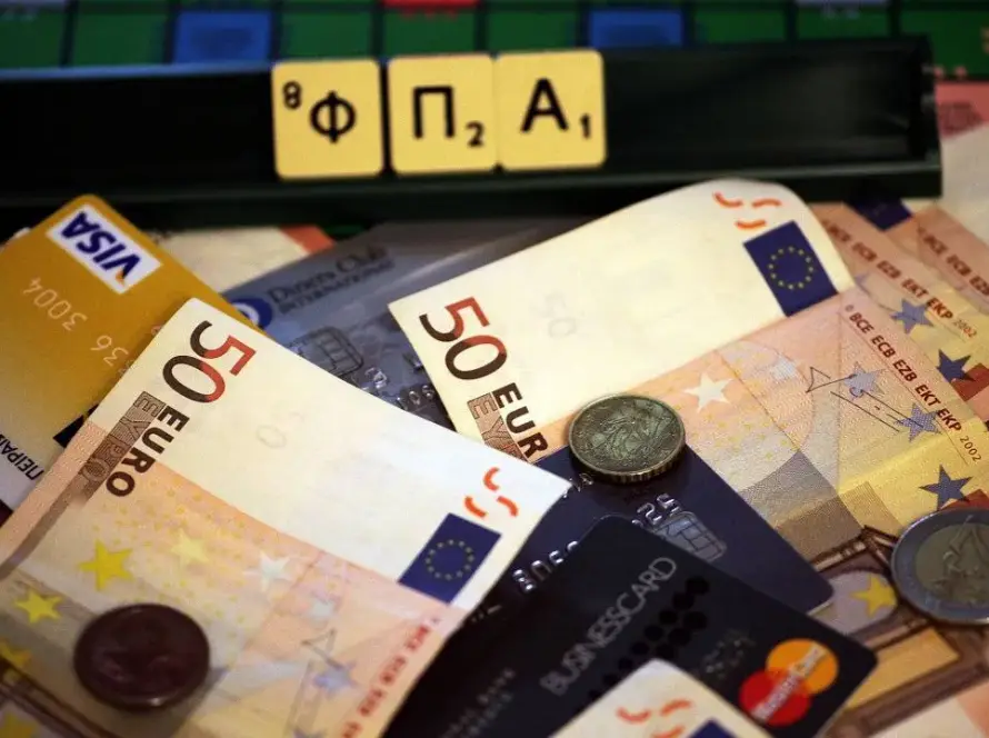 Γράμματα που σχηματίζουν τη λέξη ΦΠΑ πάνω σε χαρτονομίσματα και κάρτες